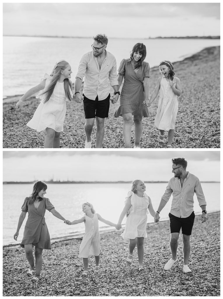 Golden Hour Family Shoot in Hampshire - Golden hour family photography in Hampshire at Meon Shore beach. A blended family of four walk hand in hand along the shoreline, smiling and laughing together, with the sun reflecting on the water behind them in black and white