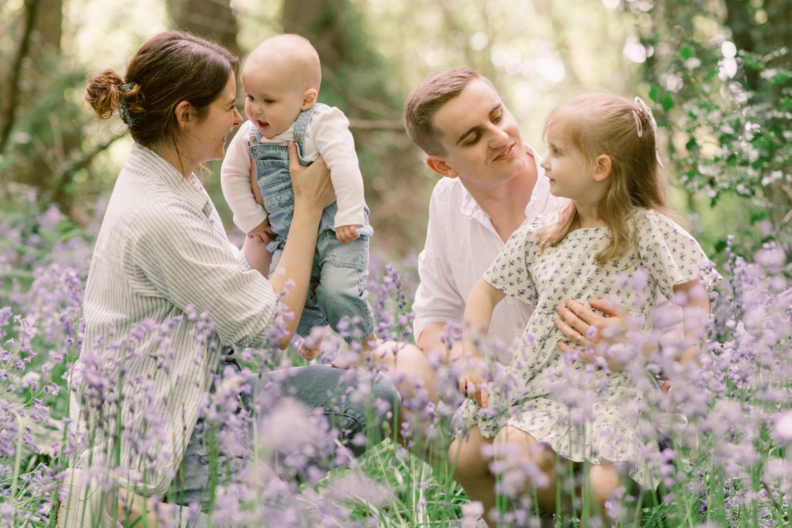 Young family smiling at each other in the bluebells | 10 Best Locations for a Family Photoshoot in Hampshire