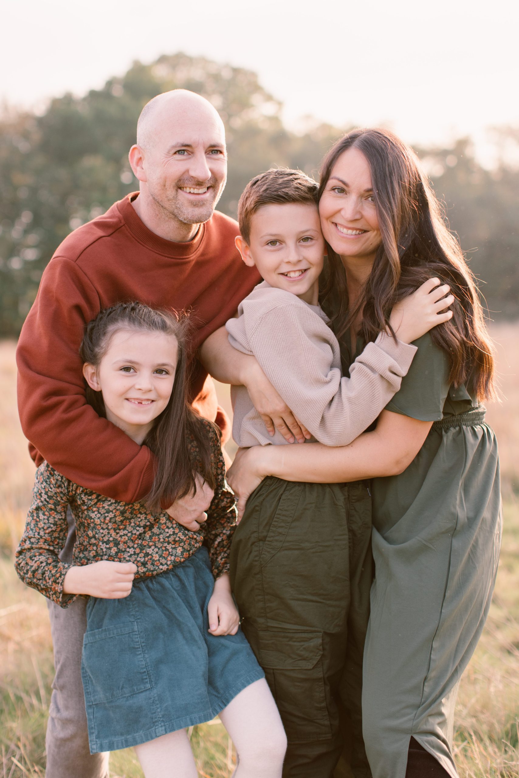 Family walking together, holding hands and looking at each other with smiles on their faces - Hampshire Family Photographer 